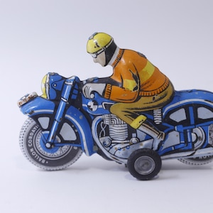 Może przedstawiać: Niebiesko-żółty motocykl zabawka z kierowcą. Motocykl ma logo "Balloon Cordat" na oponie.