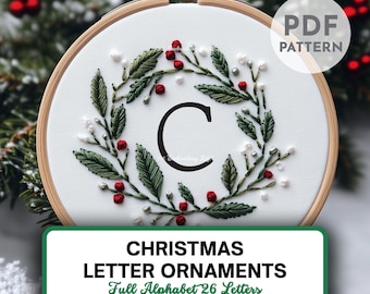 Pode incluir: Adorno de letra de Natal bordado com uma coroa verde, bagas vermelhas e contas brancas. A letra "C" está no centro da coroa. O adorno está em um aro de bordado de madeira. O texto "CHRISTMAS LETTER ORNAMENTS Full Alphabet 26 Letters" está abaixo do aro. O texto "THE Embroidery Loft" está abaixo do texto.