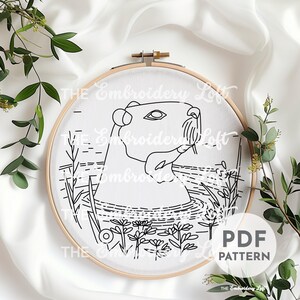 K&ouml;nnte beinhalten: Schwarzwei&szlig;es Linienkunst-Stickmuster eines Capybaras im Wasser mit Blumen. Das Muster befindet sich in einem Reifen und tr&auml;gt die Aufschrift "PDF PATTERN" unten rechts.