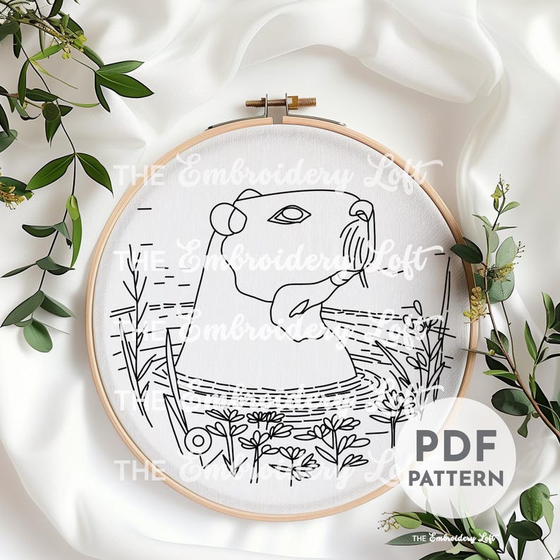 K&ouml;nnte beinhalten: Schwarzwei&szlig;es Linienkunst-Stickmuster eines Capybaras im Wasser mit Blumen. Das Muster befindet sich in einem Reifen und tr&auml;gt die Aufschrift "PDF PATTERN" unten rechts.