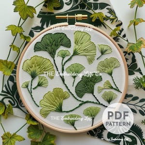 May include: A close-up of a white embroidery hoop with a green ginkgo leaf embroidery design. The hoop is on a green and white fabric background. The text "THE Embroidery Loft Co." is visible on the hoop. The text "PDF PATTERN" is visible below the hoop.