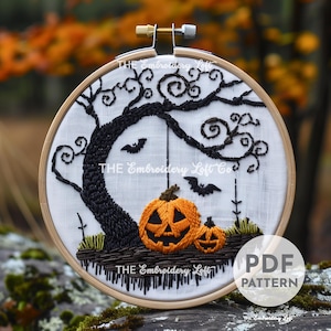 May include: Embroidery pattern for a spooky Halloween scene with a black tree, bats, and two orange jack-o'-lantern pumpkins. The pattern is in a hoop and says "THE Embroidery Loft Co."