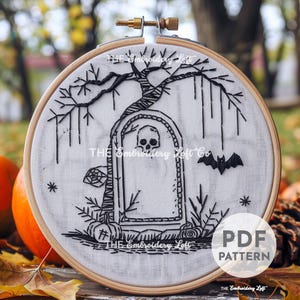 Puede incluir: Patrón de bordado en blanco y negro de un árbol espeluznante con una lápida y un murciélago. El patrón está en un aro de tela blanco. El texto "THE Embroidery Loft Co" es visible en el aro.