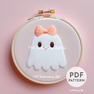 Peut inclure: Fantôme brodé avec un nœud rose, dans un cercle de broderie blanc sur fond rose. Le texte "PDF PATTERN" est dans le coin inférieur droit de l'image.