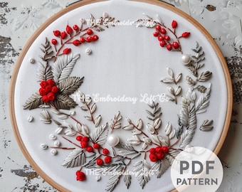 May include: A white embroidery hoop featuring a red and white floral design. The design includes red berries, white leaves, and white pearls. The hoop is on a wooden background. The text "PDF PATTERN" is in the lower right corner of the image.