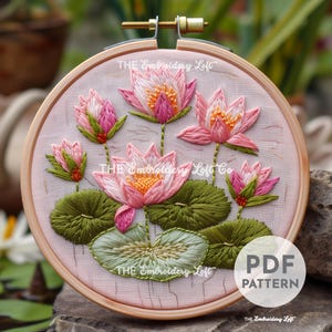 Puede incluir: Arte de bordado en aro con flores de loto rosas y hojas verdes sobre un fondo blanco. El aro es de madera y tiene una abrazadera de metal. El texto "THE Embroidery Loft" aparece tres veces en el aro. El texto "PDF PATTERN" aparece en la esquina inferior derecha de la imagen.