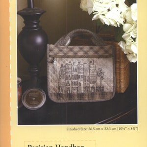 May include: A brown and white checkered fabric handbag with a stitched design of a Parisian cityscape. The handbag has a zipper closure and a brown fabric handle. The finished size is 10 1/2 inches by 8 1/4 inches.