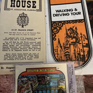 May include: A vintage postcard featuring a colorful illustration of Castillo de San Marcos in St. Augustine, Florida. The postcard has a blue border and the text "St. Augustine, Fla." in red letters.