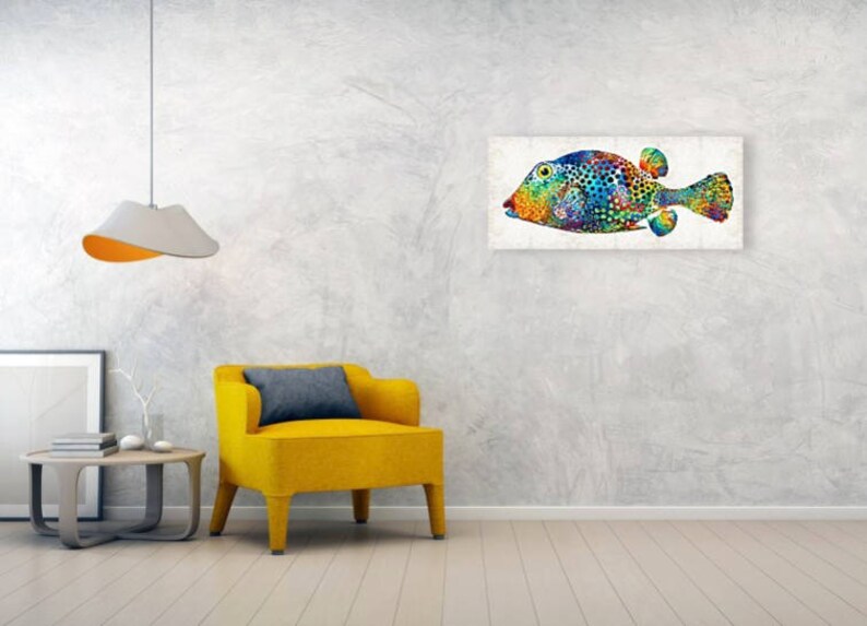 Puede incluir: Una pintura abstracta colorida de un pez sobre un fondo blanco. El pez es azul, verde, amarillo, naranja y rojo. Tiene un cuerpo redondo grande y una cabeza peque&ntilde;a y puntiaguda. El pez est&aacute; nadando hacia la derecha.