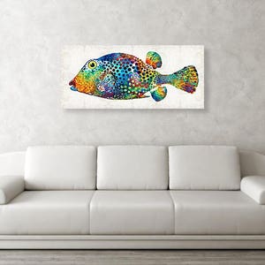 Puede incluir: Una pintura abstracta colorida de un pez con un patr&oacute;n de manchas. El pez est&aacute; pintado en tonos de azul, verde, amarillo, naranja y rojo. El fondo es gris claro.