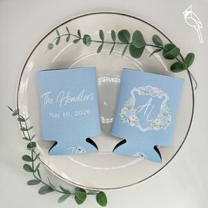 May include: A handmade wooden sign with the text "Welcome" in a playful font. The sign is painted white with a distressed finish, and features a decorative floral design in shades of pink and green. It measures approximately 12 inches wide.