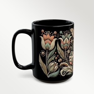 Black ceramic mug featuring a tulip floral design, ideal for tea or coffee enthusiasts. Boho-style artisan coffee cup for bohemian kitchen decor or vintage-inspired gift ideas. A charming addition to your daily routine or a thoughtful present for her