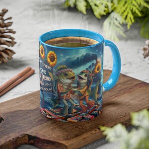 May include: A blue ceramic coffee mug with a colorful illustration of two fish dancing on a stage. The mug has the text "Now e vero che il treno passa una volta sola!" printed on the side.