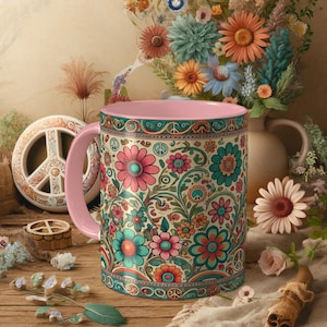 Könnte beinhalten: Eine rosa Keramiktasse mit einem Blumenmuster mit Friedenssymbolen und bunten Blumen. Die Tasse hat ein rosa Innenleben und einen weißen Hintergrund.