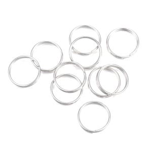 May include: A collection of silver-colored split key rings, scattered against a white background. The rings are round and made of metal. The image shows a variety of sizes and arrangements of the key rings.