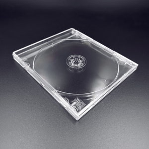 May include: A clear plastic CD case with a center hole for a disc. The case is empty and ready to hold a CD.
