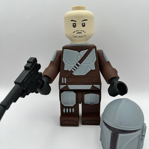May include: A large, 3D-printed figure resembling a Lego minifigure, featuring a brown and gray color scheme. The figure holds a black blaster and has a separate gray helmet. The figure's head is a light tan color with facial details.