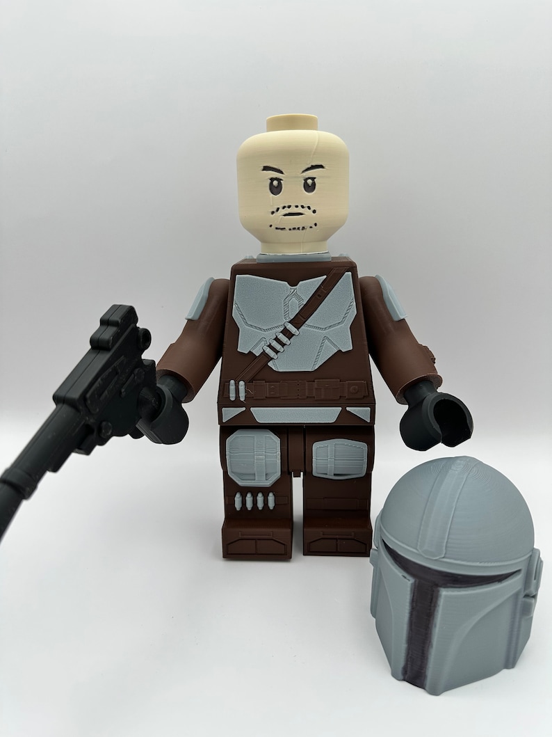 May include: A large, 3D-printed figure resembling a Lego minifigure, featuring a brown and gray color scheme. The figure holds a black blaster and has a separate gray helmet. The figure's head is a light tan color with facial details.