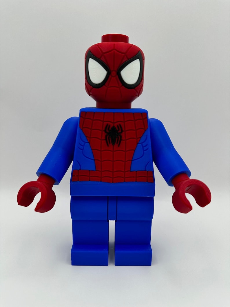 May include: A large, blocky figure of Spider-Man in a Lego style. The figure is primarily blue and red, with white eye details. The Spider-Man figure has a black spider emblem on the chest.