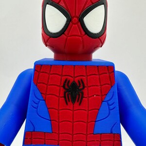 May include: A red, blue, and black Spider-Man figure. The figure has a red head with white eyes and a black outline. The torso is blue with a red spiderweb design and a black spider emblem. The arms are blue.