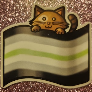 May include: A sticker of a cartoon cat peeking over a gray, white, and green flag. The flag has a green stripe in the middle and is a representation of the agender pride flag.