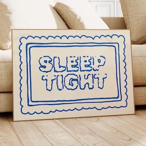 May include: A framed print with a white background and a blue border. The text "SLEEP TIGHT" is written in blue inside the frame.