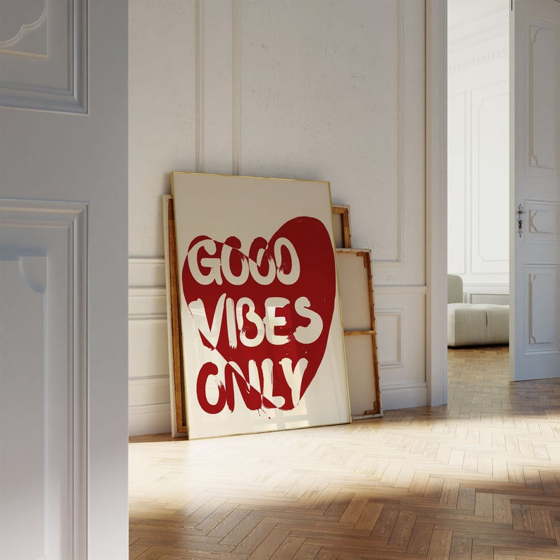 May include: A white framed poster with a red heart shape containing the text "GOOD VIBES ONLY" in white lettering.