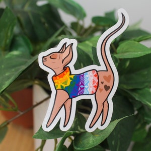 Sticker of a sphinx cat wearing a rainbow sweater.