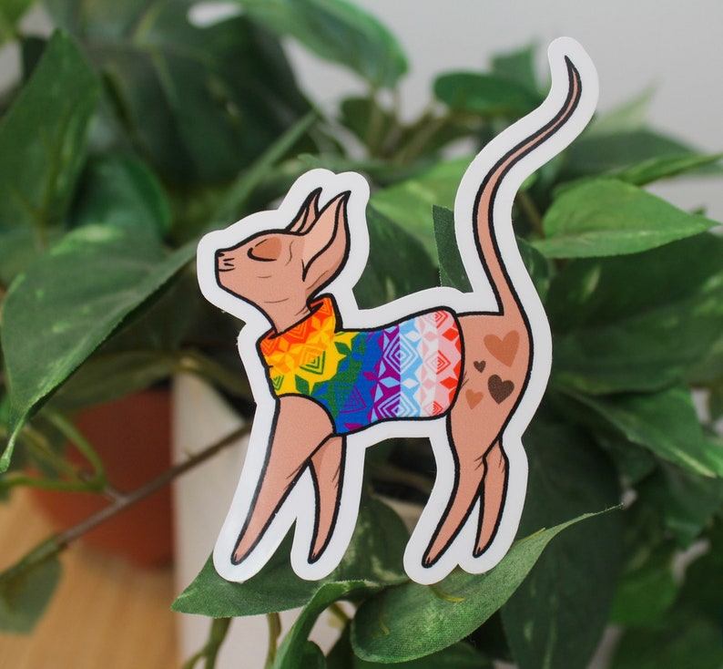 Sticker of a sphinx cat wearing a rainbow sweater.