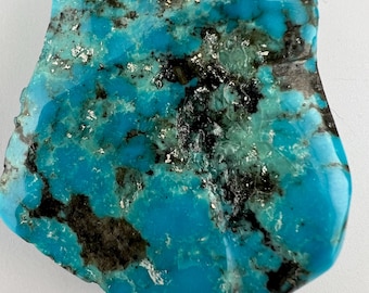 May include: A large, irregularly shaped piece of turquoise with a blue-green color and black and white matrix. The turquoise has a smooth, polished surface.