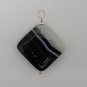 May include: Black and white agate pendant with a silver bail. The agate has a square shape and a polished finish.