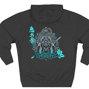 Może przedstawiać: Ciemnoszara bluza z kapturem z grafiką przedstawiającą czaszkę samuraja z hełmem, mieczami i kwiatowymi akcentami w odcieniach turkusu i bieli. W projekcie znajdują się również japońskie znaki.