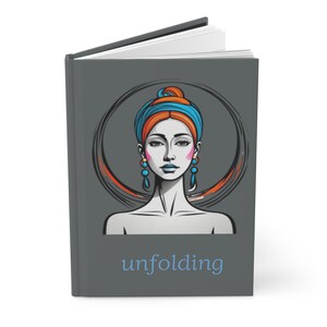 May include: A grey journal with the word "unfolding" in blue. The cover features a stylised illustration of a woman with a blue and orange head wrap, blue earrings, and a circular design in the background.