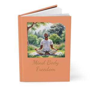 May include: A peach-colored book with a watercolor illustration of a person meditating in a green garden. The text "Mind Body Freedom" is printed on the front cover.