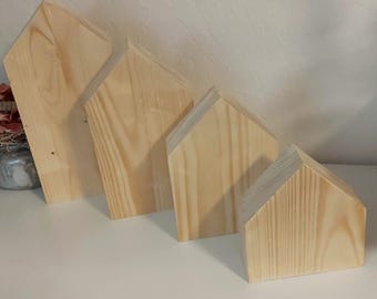 May include: Four wooden house-shaped decor pieces in various sizes, arranged in descending order from left to right. The pieces are made of natural light brown wood with a smooth finish.