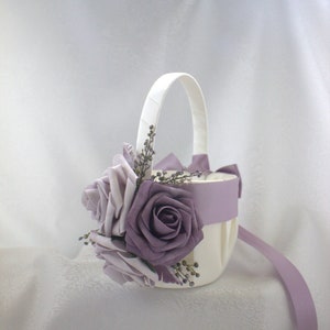 May include: A white flower girl basket with a lavender satin ribbon and purple silk roses.