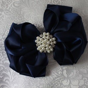 May include: A large navy blue satin bow with a pearl and rhinestone embellishment.