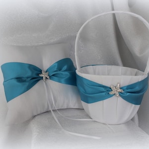 May include: White satin ring pillow and flower girl basket with teal blue satin ribbon and rhinestone starfish accents.