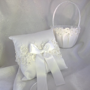 May include: White satin ring pillow with a white satin bow and pearl and lace trim. A white satin flower girl basket with pearl and lace trim.