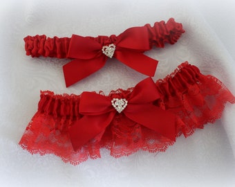 May include: Two red garters with lace and satin bows. Each bow has a rhinestone heart in the center.