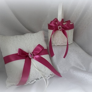 May include: White lace pillow with a pink satin ribbon and a pink rhinestone embellishment. A matching white lace basket with a pink satin ribbon and a pink rhinestone embellishment.
