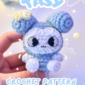 Peut inclure: Une peluche crochetée bleu clair et blanc avec de grands yeux noirs, un petit nez rose et une étoile jaune sur une oreille. L'image présente le texte TASY et CROCHET PATTERN by ellieslittleloops, avec des graphismes d'étoiles et d'étincelles.