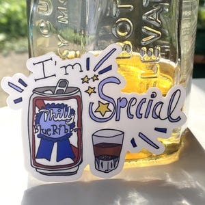 May include: A die-cut sticker featuring a cartoon beer can labeled Philly Blue Ribbon with a blue award ribbon, a small glass of amber liquid, and the text I'm Special in purple script with yellow stars and purple accent marks.