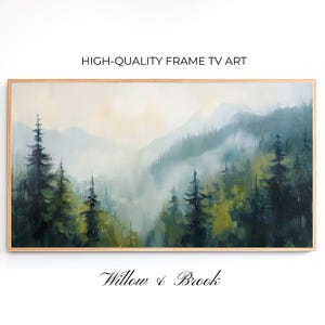 Può includere: Dipinto di paesaggio incorniciato con una scena di foresta nebbiosa con alberi sempreverdi e montagne. L'opera d'arte è nei toni del verde, blu e giallo, con il testo "HIGH-QUALITY FRAME TV ART" e "Willow & Brook" sulla cornice.