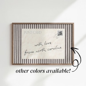 May include: A rectangular framed print featuring a vintage postcard design with the text POST CARD and the handwritten message with love from north carolina. The postcard is bordered by a vertical black and white striped pattern.