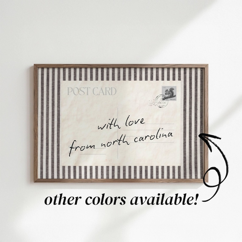 May include: A rectangular framed print featuring a vintage postcard design with the text POST CARD and the handwritten message with love from north carolina. The postcard is bordered by a vertical black and white striped pattern.