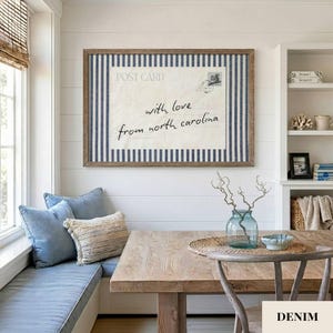 May include: A rectangular wall art piece featuring a vintage postcard design with the text "POST CARD" and "with love from north carolina" in black script, framed in wood and set against a blue and white vertical striped fabric background.