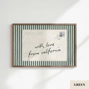 May include: A framed rectangular wall art piece featuring a vintage postcard design with the text "with love from california" in black script. The postcard is centered against a background of vertical dark green and white stripes in a wood frame.
