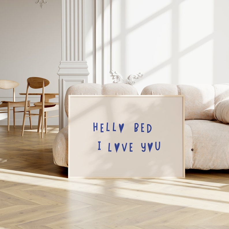 May include: A beige framed print with the text "HELL♡ BED I L♡VE Y♡U" in blue lettering on a white background.