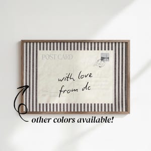 Puede incluir: Una pieza de arte mural rectangular enmarcada que presenta un diseño de postal de estilo vintage con el texto POST CARD y el mensaje escrito a mano with love from dc. La postal se sitúa sobre un fondo de rayas verticales marrón oscuro y blanco.